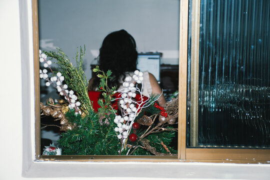 Portrait through window with garland of woman doing home office