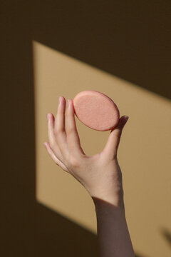 Minimalist Hand Holding Round Soap Bar Against Neutral Background