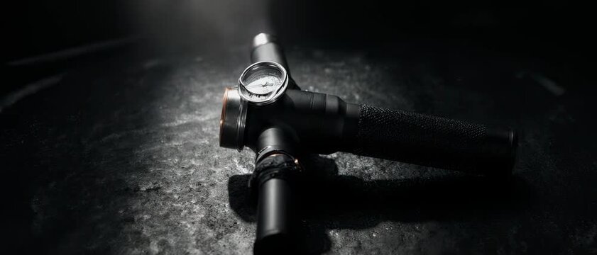 Pro-Grip Pump. Premium Football Gear on Dark Studio Background. Performance Branding. Matte-black hand pump with a metallic pressure gauge, set in a dark industrial atmosphere with a single spotlight
