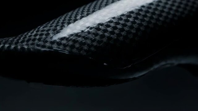 Shin Guard Texture. Premium Football Gear on Dark Studio Background. Sports Protection Detail. A close-up of carbon-style shin guard texture, set in a dark studio environment
