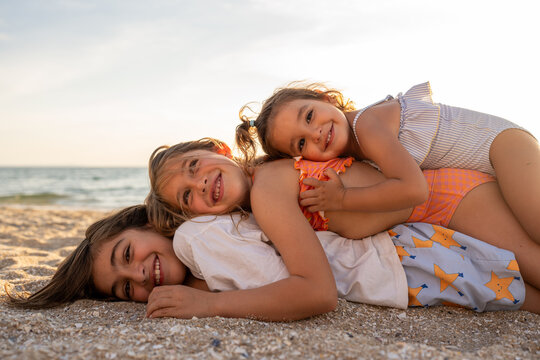 Three kids on the top of each others at the beach