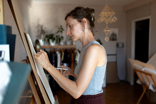 a woman paints on a canvas in a room