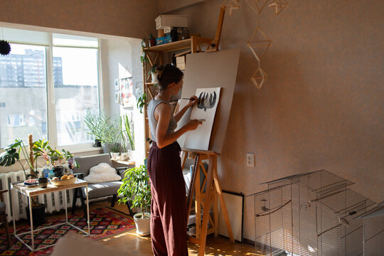 a woman paints on a canvas in a room