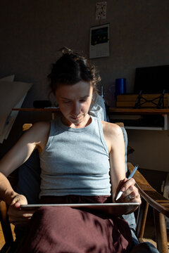 the woman is sitting  and drawing  in the room