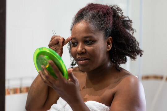 a woman removing hair from her eyebrows