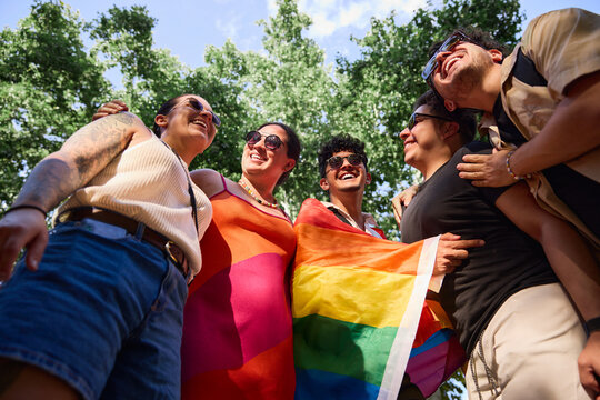 Group of friends holding a rainbow flag in a circle at a pride parade