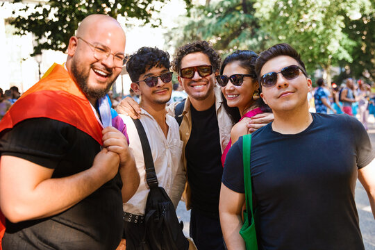 Smiling group posing with a rainbow flag at pride parade