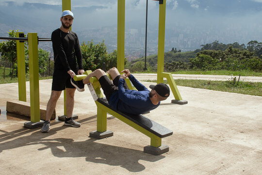 Man doing ab exercises on outdoor gym with friend