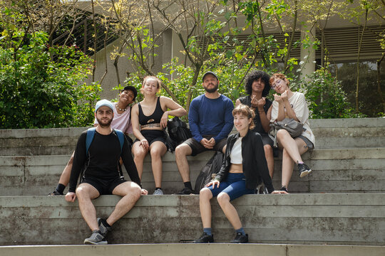 Group of friends in sportswear posing on outdoor bleachers 