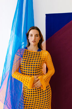 Mod odel posing in colorful studio with flowing blue fabric