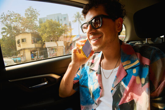 Man smiling while talking on the phone in a car ride