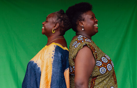 mother and daughter standing back-to-back laughing