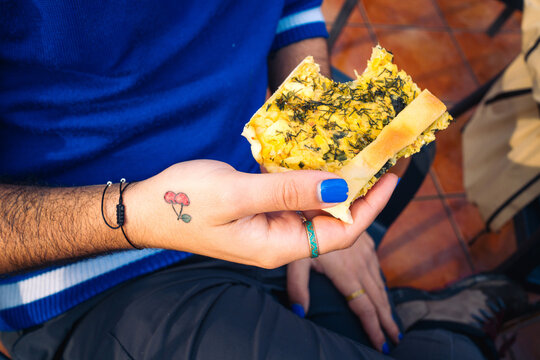 Hand holding a piece of homemade vegetable tart with tattoos