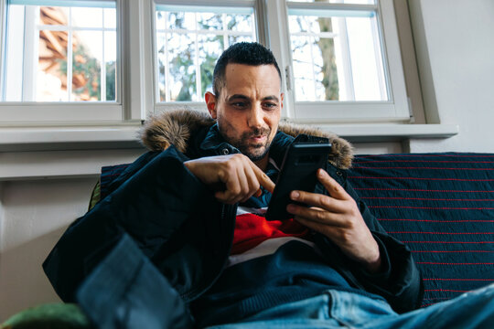 Man scrolling his smartphone with funny grimace on face