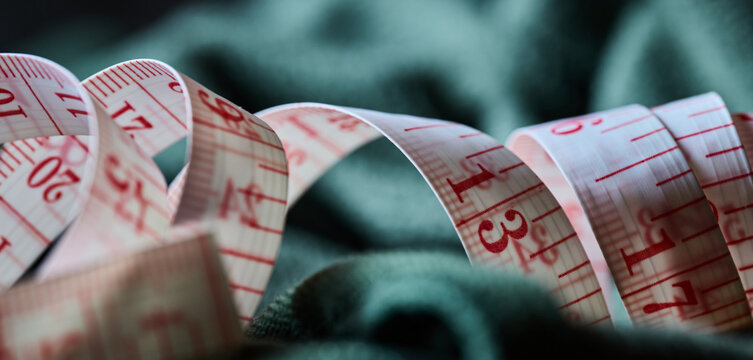 White measuring tape on green fabric macro
