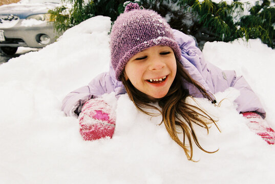 Happy film portrait of girl playing outside in a pile of fresh snow