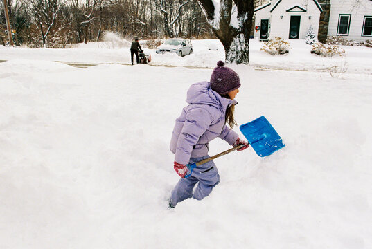Child runs and plays outside with snow shovel after winter storm