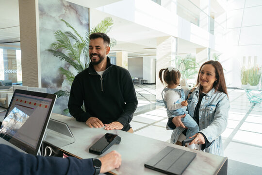 Family checking in at hotel reception smiling and beginning vacation