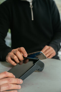 Customer paying with mobile phone on pos terminal in hotel