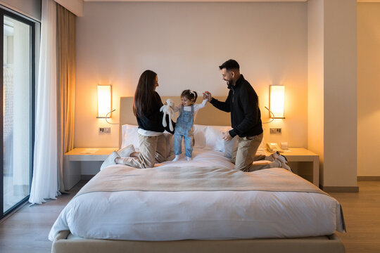 Happy family playing on bed in hotel room