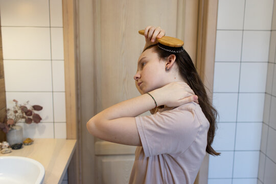 Teenage girl combing her hair in the bathtub