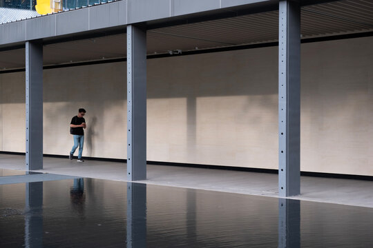 A solitary man strolls along a sleek, covered walkway