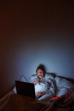 Working or Watching? Woman in Bed with Laptop.