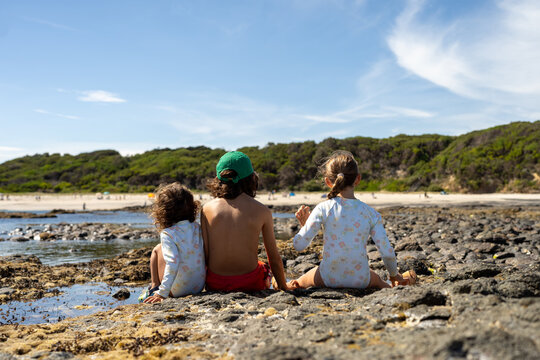 Siblings sitting together looking for crabs in tide pools