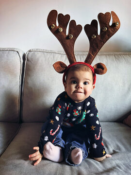 baby in Festive christmas Reindeer Antlers on Sofa