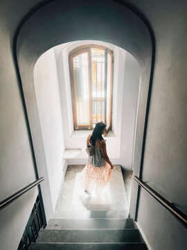 Woman on Staircase in Arched Hallway