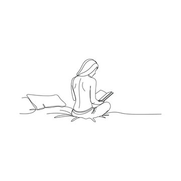 Woman sitting comfortably reading a book with pillow on floor