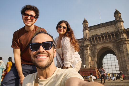 Friends taking selfie in front of Gateway of India monument in Mumbai