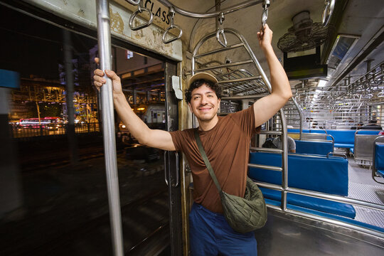 Smiling passenger holding handrails in empty subway train in Mumbai
