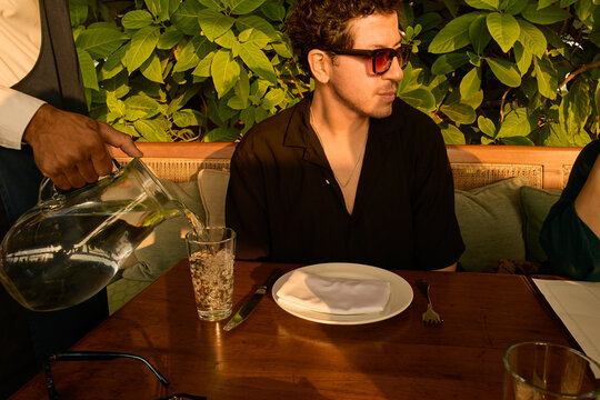 Man dining at restaurant with greenery backdrop