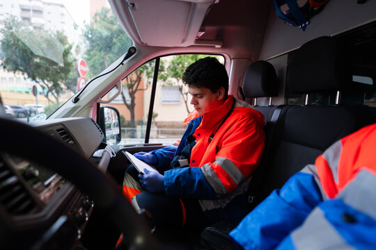 Paramedic reading medical report inside ambulance