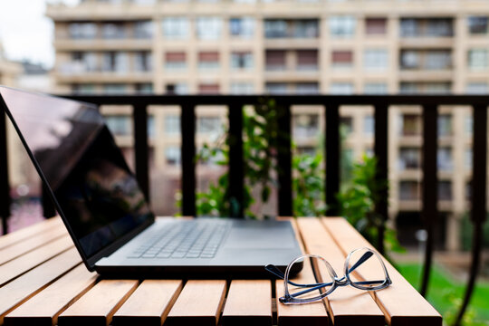 Eyeglasses and laptop on home terrace table