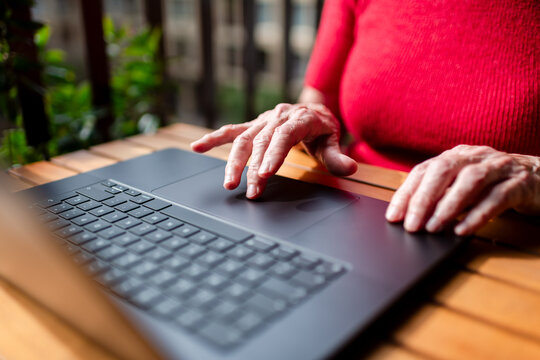 Close up of senior hands using modern laptop 