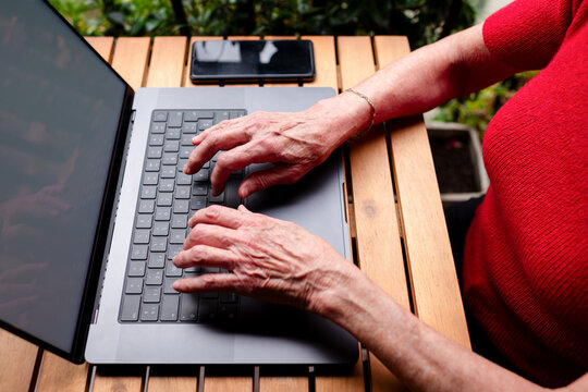 Senior hands typing on modern laptop keyboard