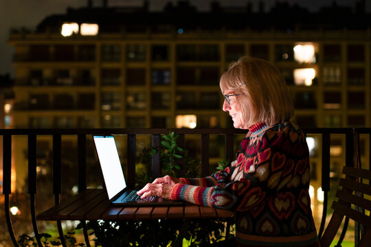 Relaxed senior woman using laptop at home terrace