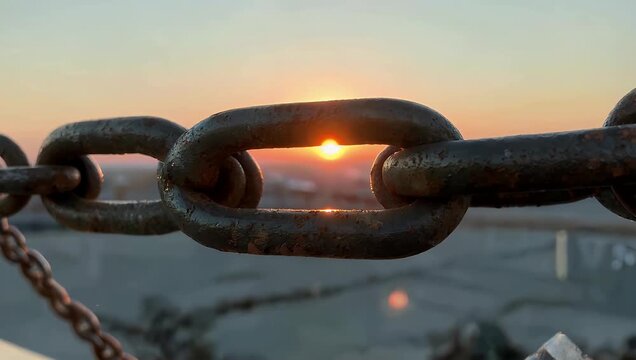 High quality 4K footage of strong iron chain coming into sharp focus against backdrop of fading sunset emphasizing textures metal detail atmospheric light industrial cinematic stock 