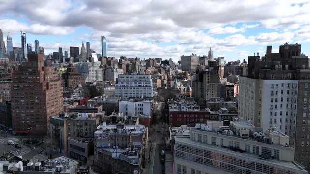 Amazing aerial footage pulling back over the streets and buildings of manhattan, revealing the iconic new york city skyline with its impressive skyscrapers under a cloudy sky