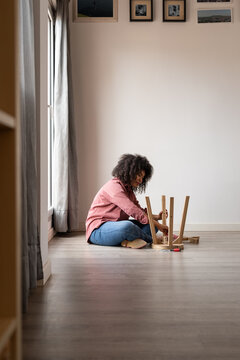 Woman assembling wooden stool in empty room