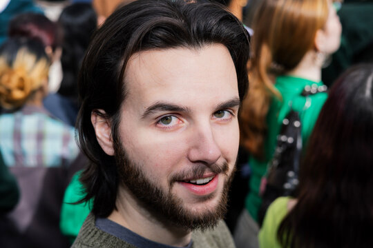 Man looks at camera with ambivalent expression during St Patrick's Day