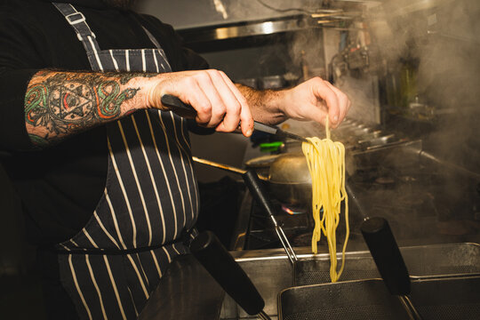 Chef using tongs to pick up pasta