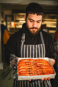 Bearded Chef holding a tray of orange prawns