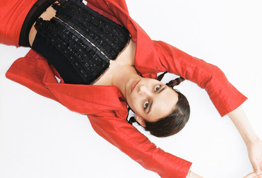 Fashion model showcases bold red outfit lying on white surface 