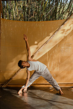 Man Practicing Triangle Pose Yoga in Outdoor Studio