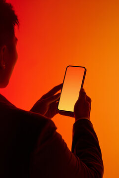 A person holds a glowing smartphone against a gradient orange