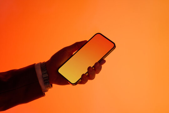 A man's hand elegantly presents a smartphone on a gradient background