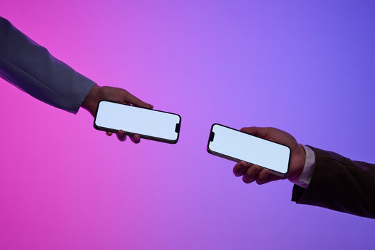 Two business people holding modern smartphones with blank screens